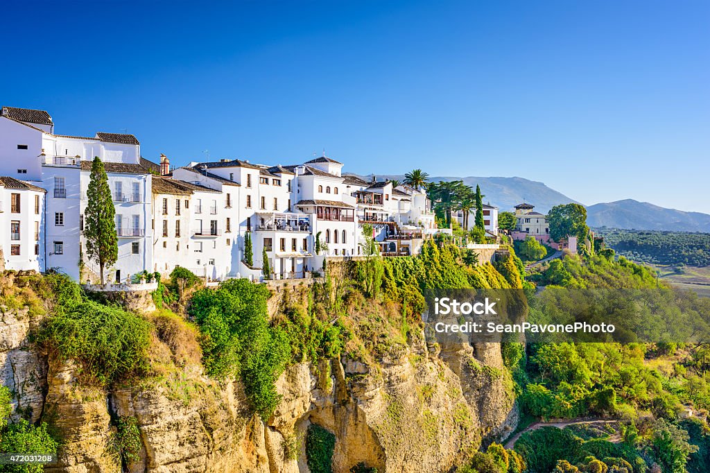 Houses on a cliff in Ronda, Spain surrounded by green trees Ronda, Spain old town cityscape on the Tajo Gorge. Spain Stock Photo