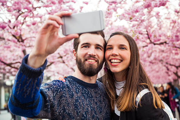 istock Young couple fall in love under a beautiful cherry tree 472031324