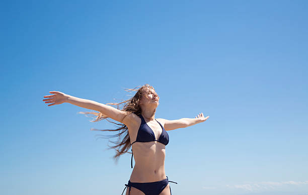 istock Beautiful young woman open arms under the blue sky 472034098