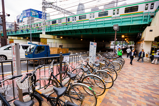Tokyo, Japan  - October 29, 2010: Bicycles parked on Tokyo Street, Shinjuku district. People walking on the street, train is moving on the bridge