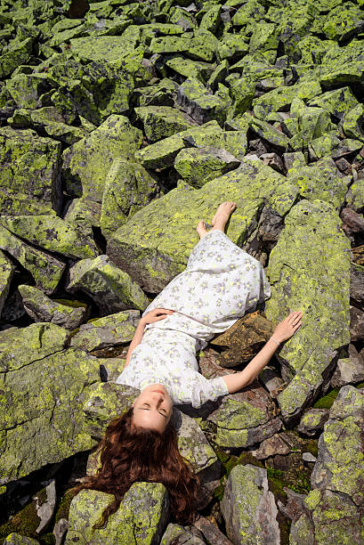 istock Beautiful young woman lying on stone 472034764