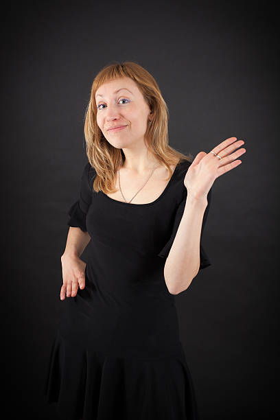 Studio portrait shot with black background. In this headshot the model is serious and looking at the camera. She is sitting on a chair. The main front flashlight has a blue gel and the hair flashlight at the back has a purple gel.
