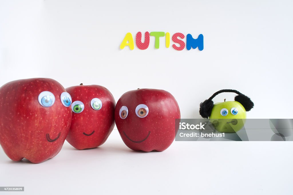 Autism Apple Series The red apples are grouped together talking about the green apple because it is different. The red apples are focused only on what is different about the green apple, and not about what similarities they share. The green apple is wearing headphones so it does not become overstimulated. The green apple is a model of a human with autism. The word autism is placed in the background. The red apples are smiling and laughing and the green apple is crying. Anger Stock Photo