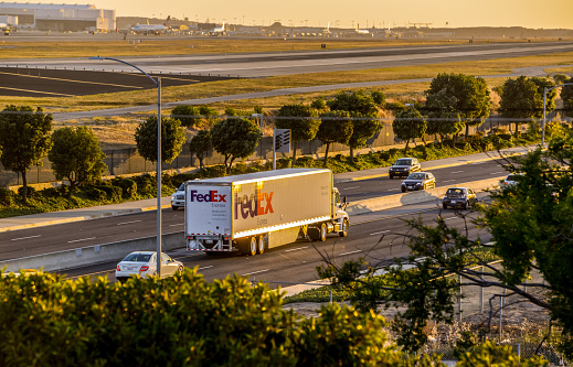 Los Angeles, USA - May 13, 2013: FedEx Truck on the road, sunset, moving along  Los Angeles Airport, located on its left side. 