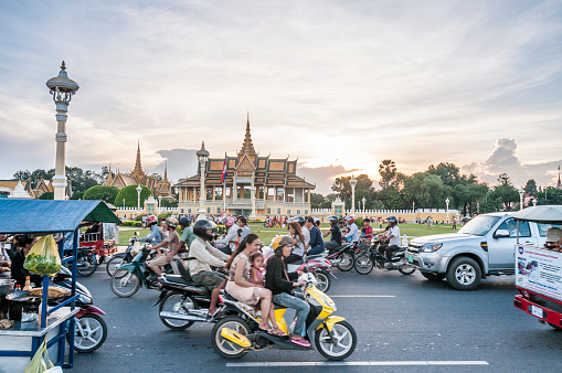Phnom Penh, Cambodia - November 24, 2013: Traffic in front of The Royal Palace In the river front area of Phnom Penh, Cambodia. The river front in Phnom Penh is a fast developing tourist area with many hotels, restaurants, bars and new developments being built around the ancient Palace and Temple