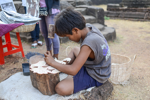 Siem reap, Cambodia - April 03, 2013 : A young worker making the leather carving at Angkor wat.