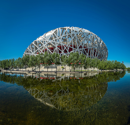 Beijing, China - 25th September 2013: The iconic steel lattice of Beijing's National Stadium, or Bird's Nest, reflecting in the tranquil waters of Olympic Park lake in the heart of China's vibrant capital city.