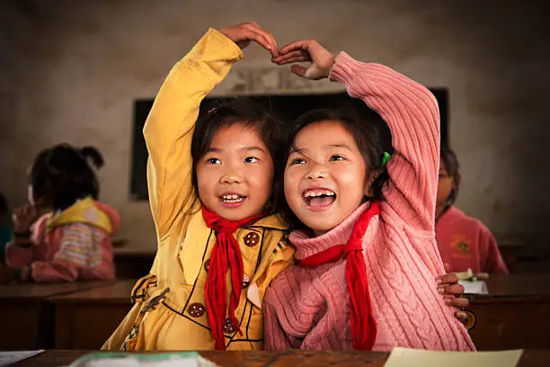 Chinese school children in a rural village school,, making a heart shape with their hands...