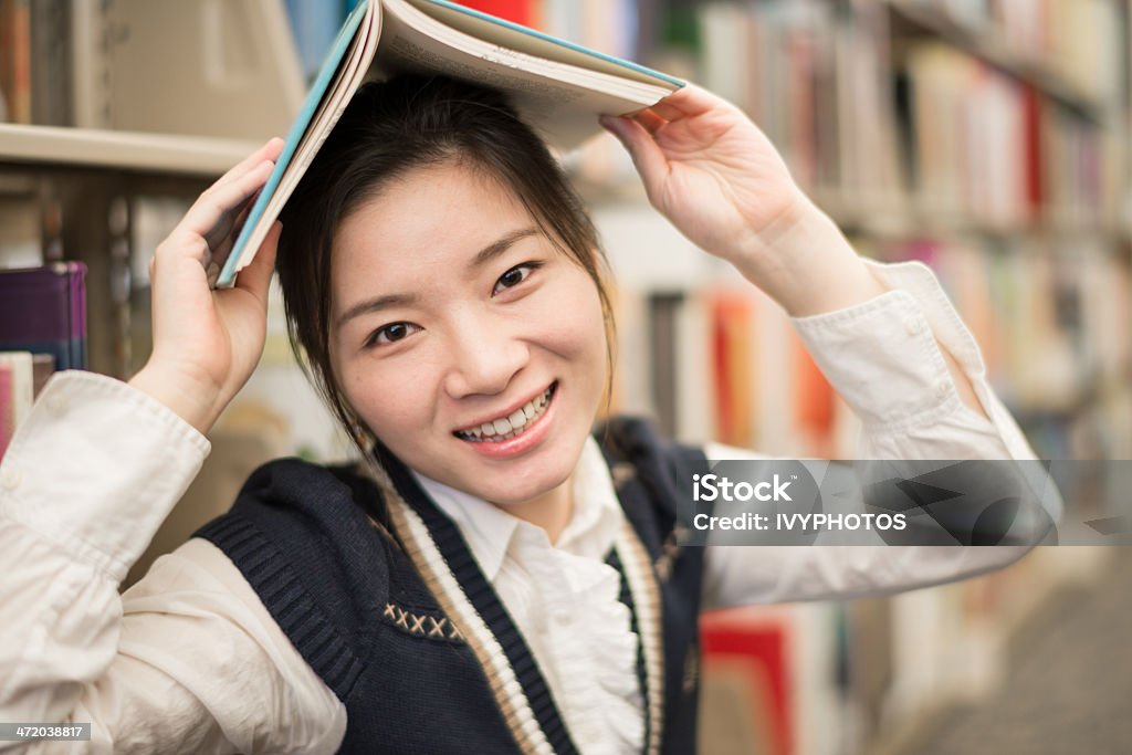 Jeune fille tenant un livre de bibliothèque-dessus de la tête - Photo de Adulte libre de droits
