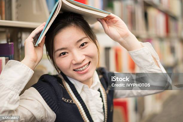 Photo libre de droit de Jeune Fille Tenant Un Livre De Bibliothèquedessus De La Tête banque d'images et plus d'images libres de droit de Adulte