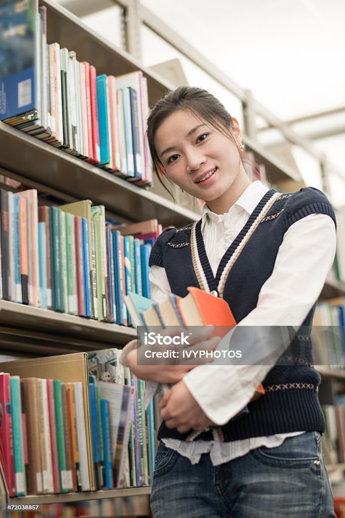 Estudiante sostiene junto a la estantería de libros - Foto de stock de Adulto libre de derechos