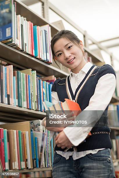 Estudiante Sostiene Junto A La Estantería De Libros Foto de stock y más banco de imágenes de Adulto