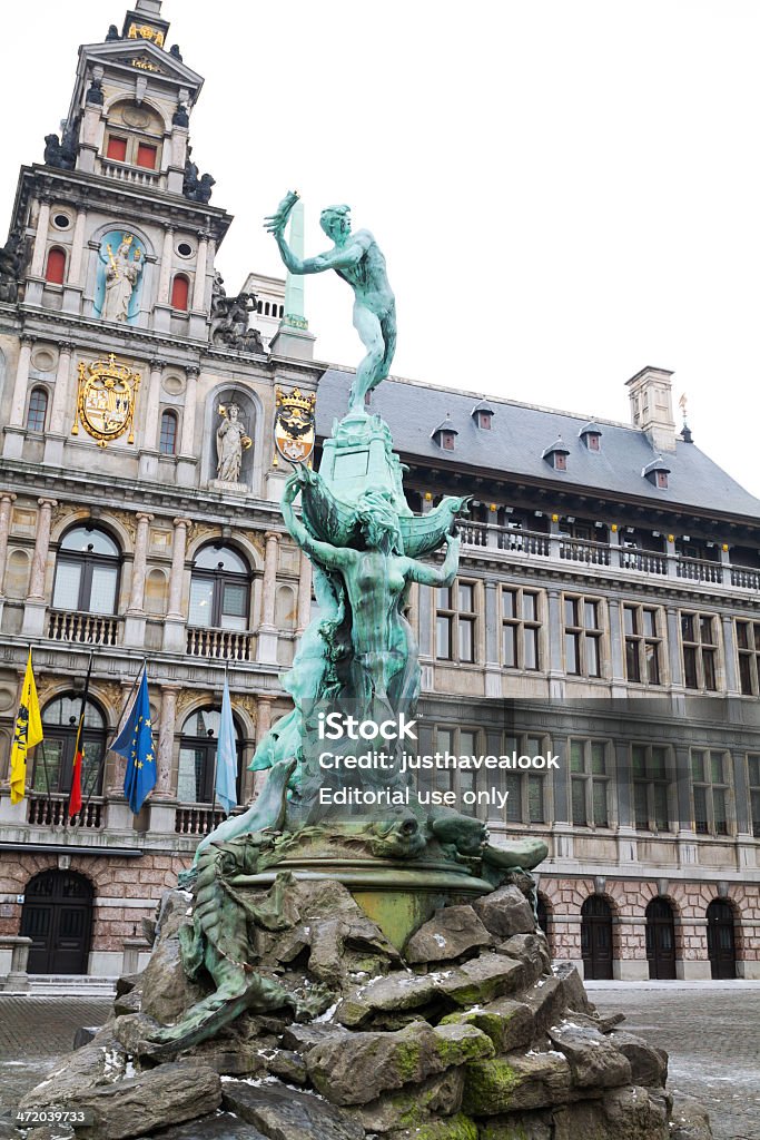 Brabo fountain and town hall of Antwerp Antwerpen, Belgium - February, 9th 2012: Famous town hall of Antwerp built by Cornelis Floris de Vriendt and several other architects and artists. It is seated at square Grote Markt.  Center of facade above entrance shows statues of Justice, Prudence, and the Virgin Maryand also the coats of arms of the Duchy of Brabant, the Spanish Habsburgs, and the Margraviate of Antwerp. In foreground is Brabo Fountain made by architect Jef Lambaux in 1887 (Showing mythical hero Brabo throwing giants hand after cutting it off.)  Antwerp City - Belgium Stock Photo