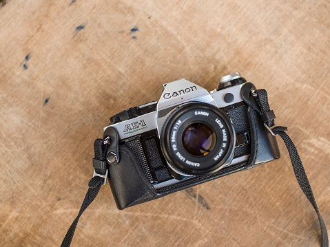 Antalya, Turkey - November 1, 2013: Product shot of a Canon AE-1 Program analog SLR camera with 50mm lens attached on wooden background