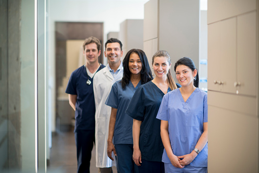 A group of doctors, nurses, and or dentists and professional assistants posing for a picture in a medical clinic.