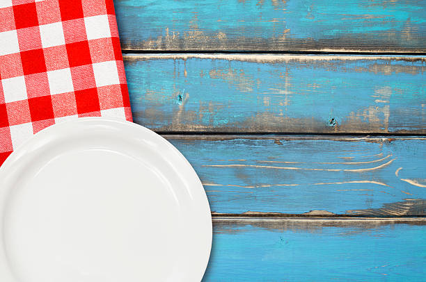 istock Red Checked Napkin with Dish on Blue Wooden Picnic Table 472042312