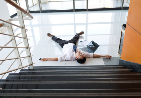 Man slips falling on wet floor in a modern office building.