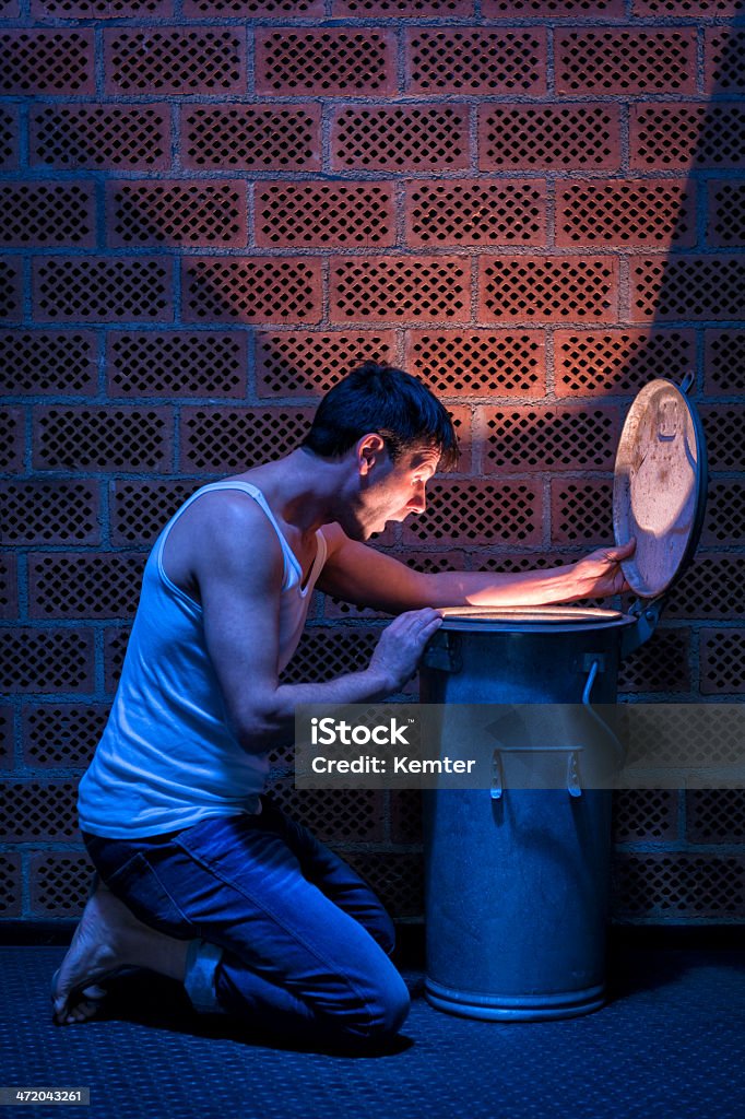 surprised man looking into glowing garbage can kneeling man looking surprised into glowing garbage can 30-39 Years Stock Photo