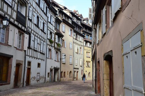 Colmar, France - Oct 17 2013. A pedestrian is walking along a street lined with timer-framed houses