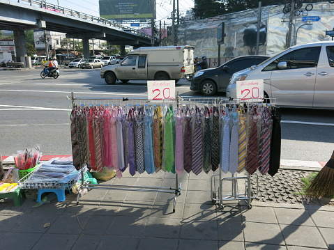 Bangkok, Thailand – November 27, 2013: Selling ties on a sidewalk in Bangkok. People walk on a sidewalk in the morning, Bangkok, Thailand. Some people buy food for breakfast from street vendors on the sidewalk. 