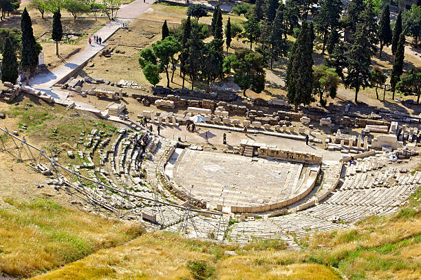 Athens, Greece - April 11, 2010: The Theatre of Dionysus on the southern slopes of the Acropolis in it's heyday could seat up to 25,000 people.  Some tourists are seen admiring the ruins