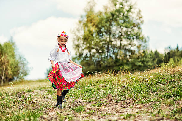 Little girl wearing traditional folk costume from the region of Cracow, Poland running on meadow.