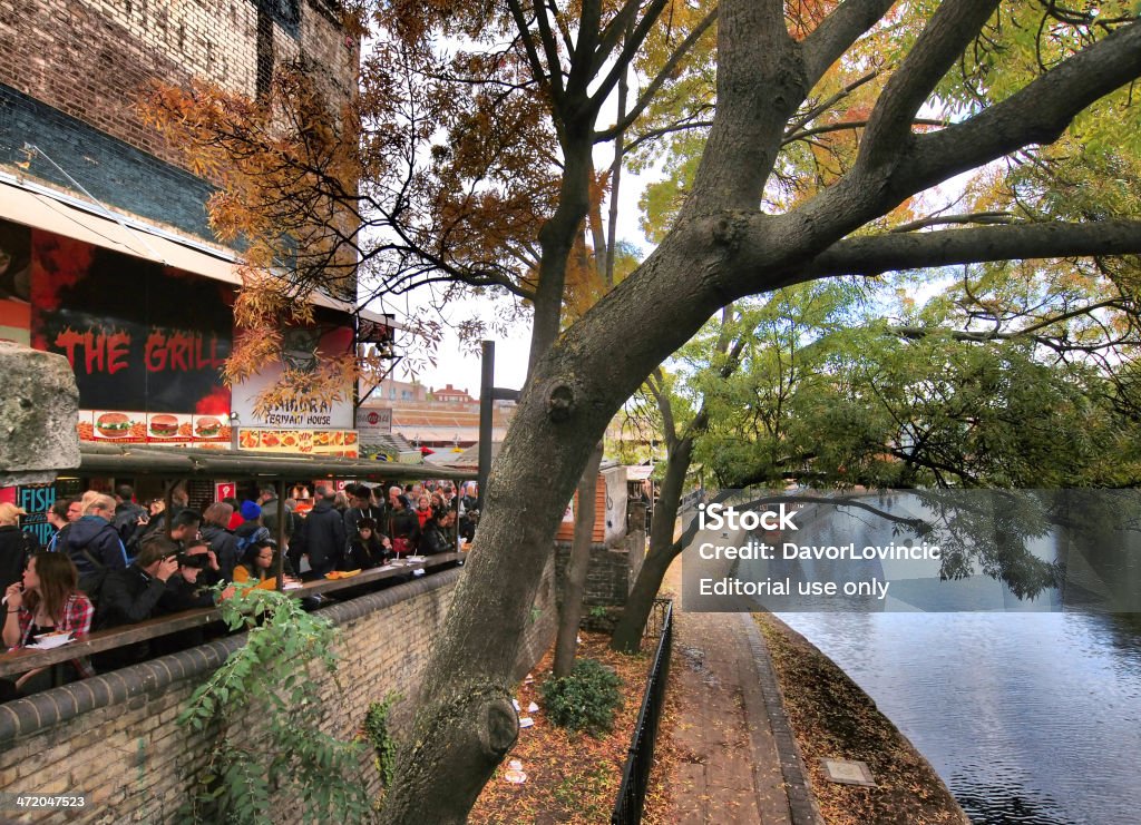 Camden food London, United Kingdom - October 30, 2013: View from Camden Street Bridge on Regent's Chanel on right and people in front of fast food restaurants. In middle is tree framing photo in two frames, in background is surrounding house and grey sky. Border - Frame Stock Photo