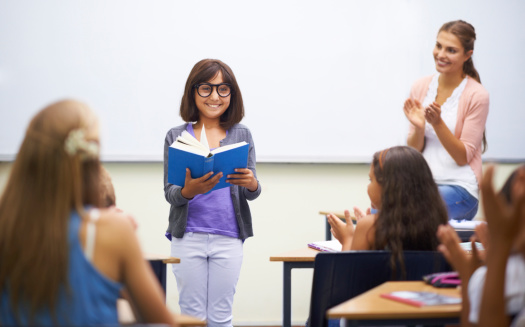 Confident young female professor talks to students in classroom
