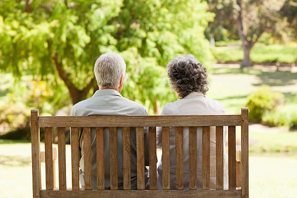 istock Old couple sitting on bench in park 472051049