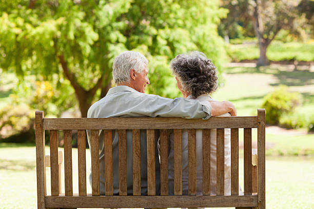 istock Man with hand around woman sitting on bench 472051055