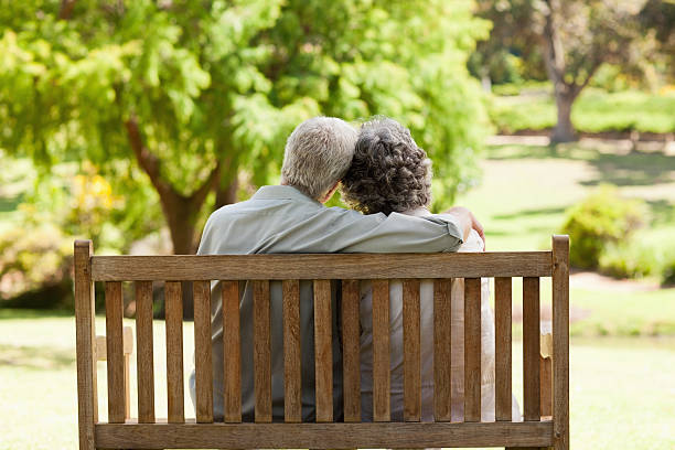 istock Old couple hug on bench in park 472051061