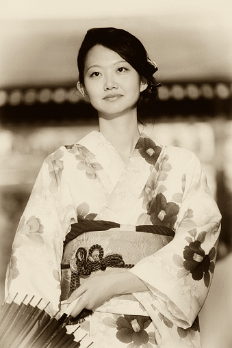 A Japanese woman standing on a street in Tokyo.  Processed with grain and tone to recreate the look of an old photograph.