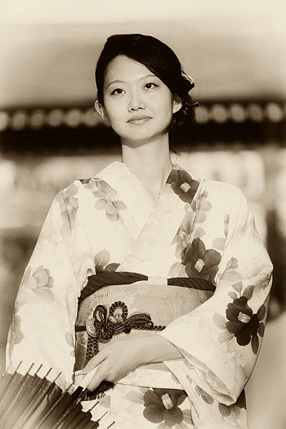 Japanese Woman A Japanese woman standing on a street in Tokyo.  Processed with grain and tone to recreate the look of an old photograph. kimono photos stock pictures, royalty-free photos & images