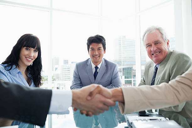 istock Three smiling business people looking at serious executives shak 472051537