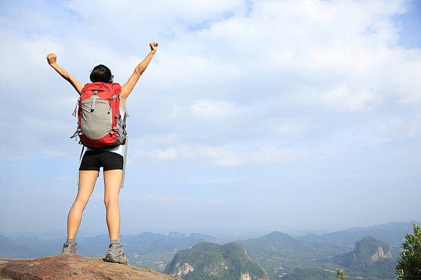 istock cheering woman hiker open arms at mountain peak 472052680