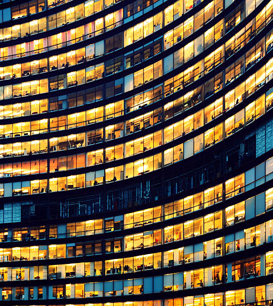 edificio de oficinas en la noche con ventanas iluminado - big city life fotografías e imágenes de stock