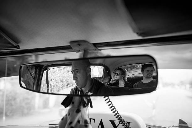 Vinales, Cuba - December 10, 2014: Two travelers from Europe sit in the backseat of a 1955 Plymouth used as a taxi in Cuba. The driver is taking his passengers from Vinales to Cayo Jutias, in Pinar del Rio Province.