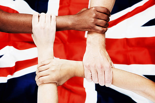 istock Four multiracial British hands linked together on Union Jack 472054503