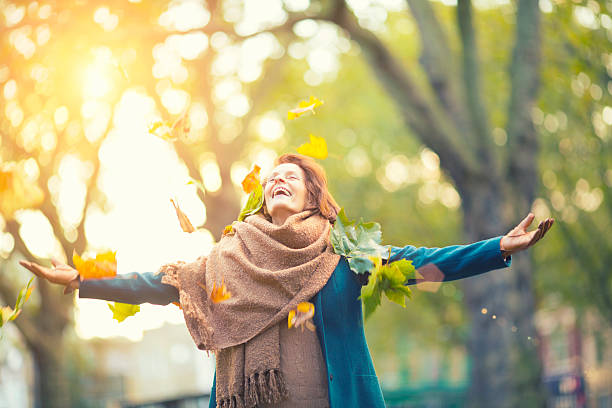 istock Senior Woman Throwing Maple Leaves 472055319