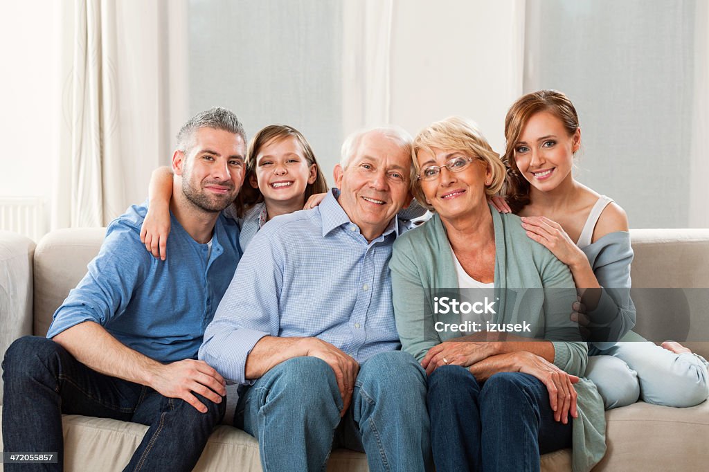 Multi generation family Grandparents, patents and cute girl sitting on sofa at home and smiling. 30-39 Years Stock Photo