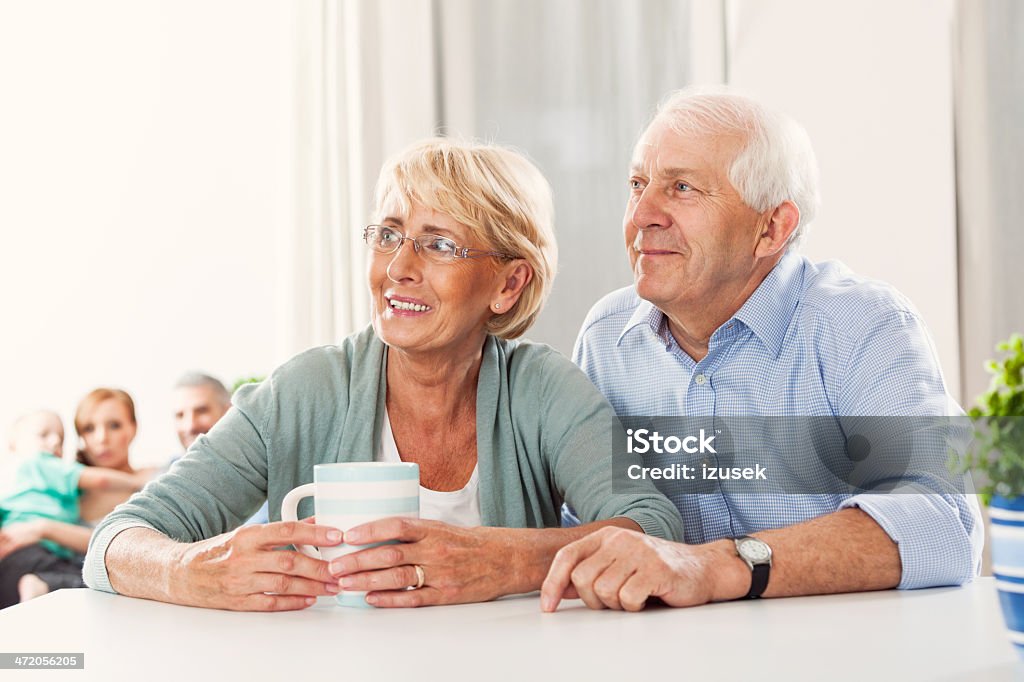 Senior couple Portrait od cheerful senior couple sitting by the table at home, looking away. 60-69 Years Stock Photo