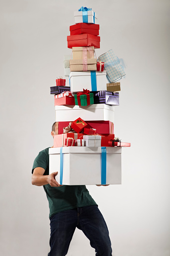 Man carrying stack of Christmas presents, studio shot.