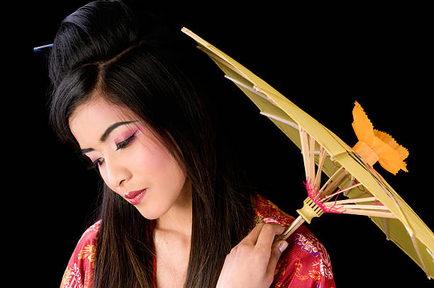istock Geisha with yellow parasol looking down. 472057315