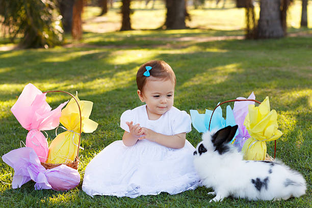 istock Smiling baby girl looking at rabbit with Easter chocolate eggs 472058038