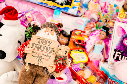 Suffolk, Virginia, USA - December 4, 2013: A horizontal studio shot of a large collection of American brand toys with a Santa figurine at the front, holding a sign promoting a Toy Drive for the holidays.  