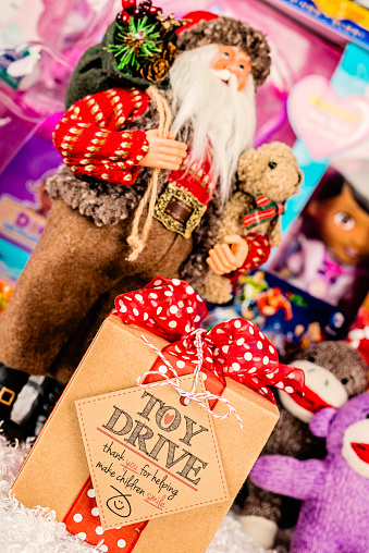 Suffolk, Virginia, USA - December 4, 2013: A vertical studio shot of a large collection of American brand toys with a Santa figurine at the front. In front of Santa is a gift box with a gift tag promoting a Toy Drive.   