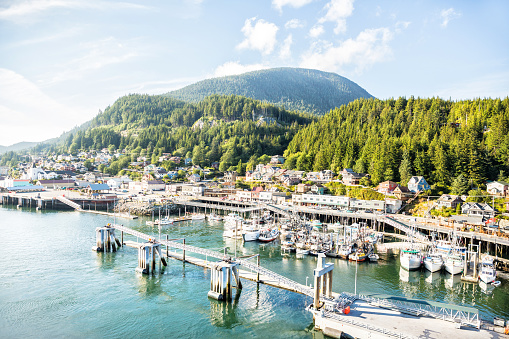 Fishing boats are docked in the port of Ketchikan, Alaska.  Homes overlook the port. RM