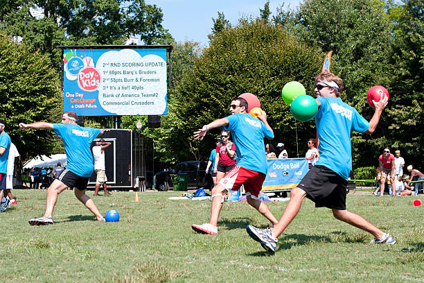 Atlanta, GA, USA - September 7, 2013:  Three young men simultaneously wind up to throw balls during a dodge ball game at A Day For Kids, an event where adults play kids games to benefit the Boys and Girls Clubs of America.