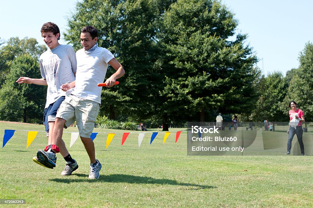 Two Young Men Compete In Three-Legged Race At Summer Fundraiser Atlanta, GA, USA - September 7, 2013:  Two young men compete in the three-legged race at A Day For Kids, an event where adults play kids games to benefit the Boys and Girls Clubs of America. Three Legged Race Stock Photo