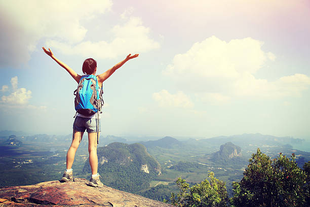 istock cheering woman hiker open arms at mountain peak 472064044